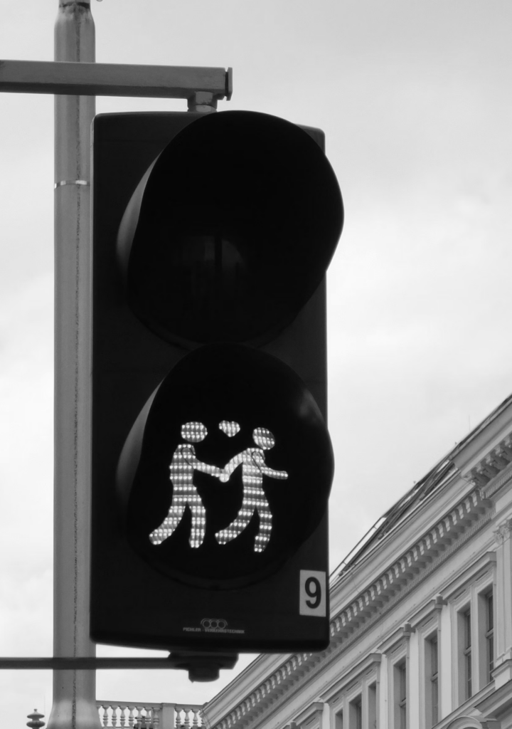 Immagine evocativa di un semaforo che trasmette emozioni attraverso l’immagine di due persone che si prendono per mano per attraversare la strada.